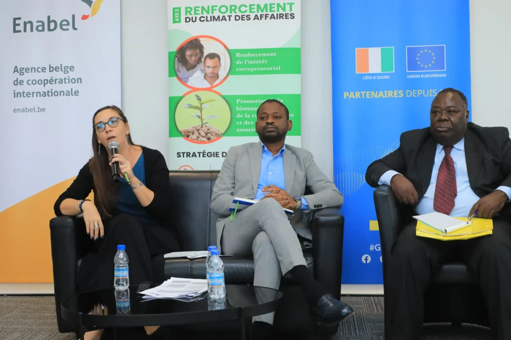 Vabicui — Trois intervenants assis autour d’une table lors d’une conférence sur le renforcement du climat des affaires en Côte d’Ivoire, avec un panne