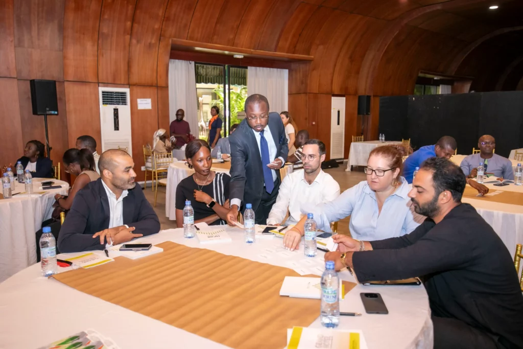Vabicui — Un groupe de cinq personnes, dont un homme en costume bleu debout au centre, discute autour d'une table de conférence. Les participants, ass